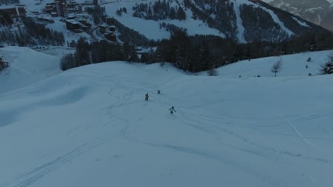 Aerial-drone-view-following-a-group-of-snowboarders-riding-off-road.-Sunset-time